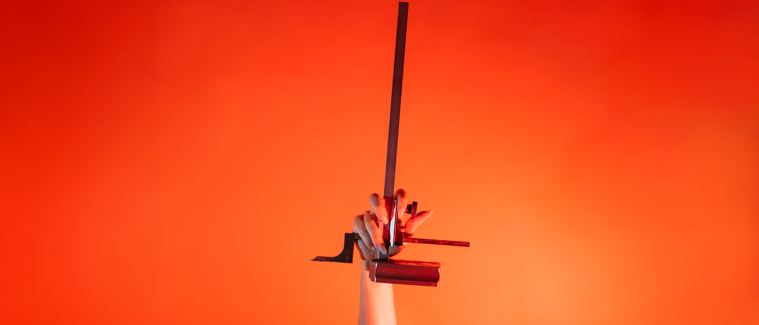 Ein Arm ist vor orangenem Hintergrund senkrecht nach oben gestreckt und in der Hand wird ein Höhenanreißer gehalten.