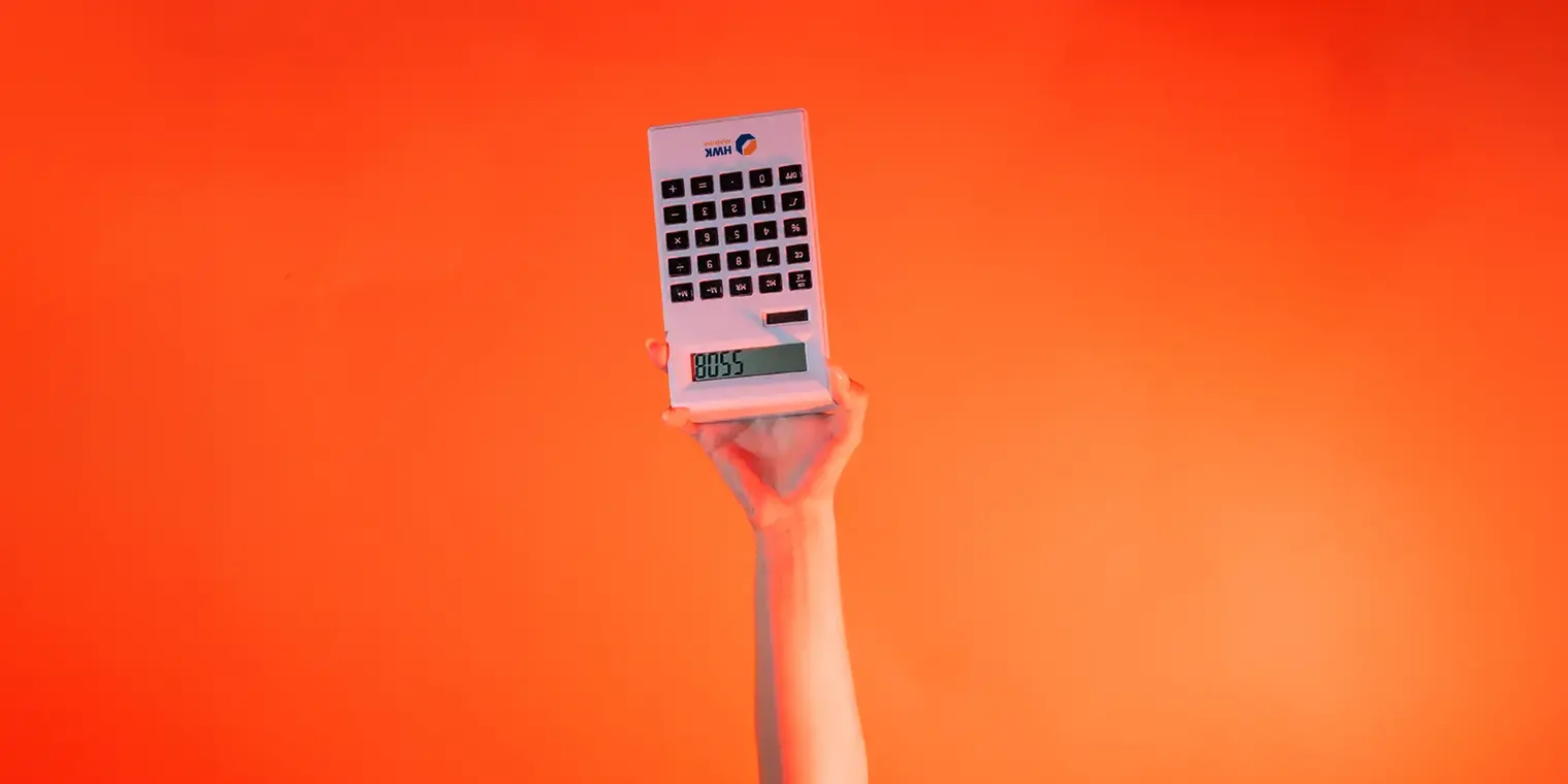 Ein Arm ist vor orangenem Hintergrund senkrecht nach oben gestreckt. Die Hand hält einen digitaler Taschenrechner umgedreht. 