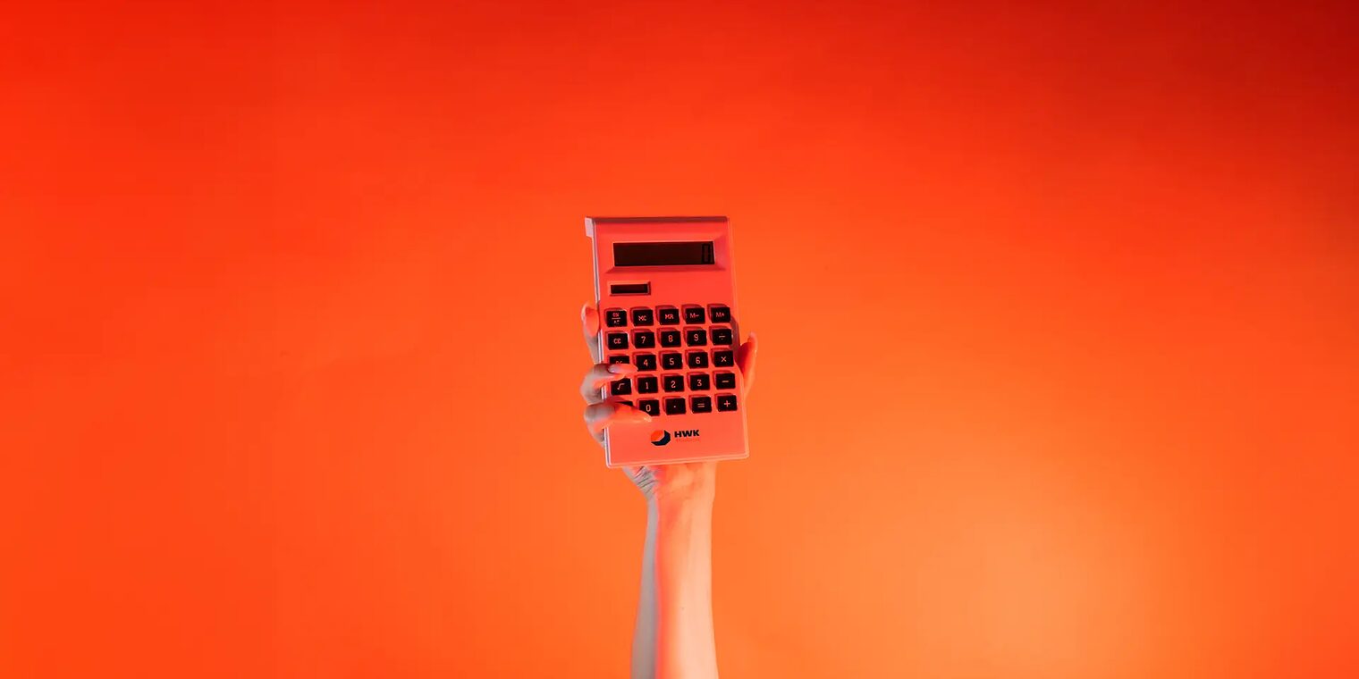 Ein Arm ist vor orangenem Hintergrund senkrecht nach oben gestreckt und in der Hand wird ein Taschenrechner gehalten.