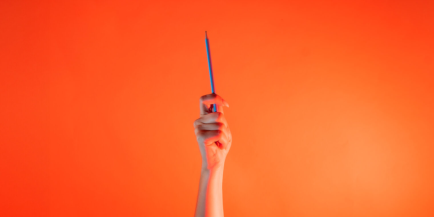 Ein Arm ist vor orangenem Hintergrund senkrecht nach oben gestreckt und hält in der Hand eine Bleistift.