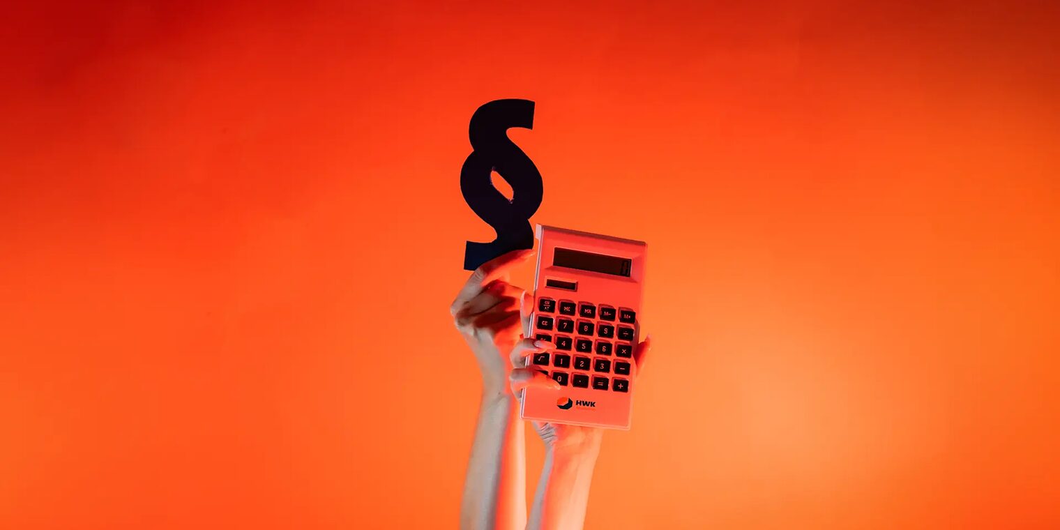 Zwei Arme sind senkrecht nach oben gestreckt und halten in den Händen eine Taschenrechner und einen Paragraphen.