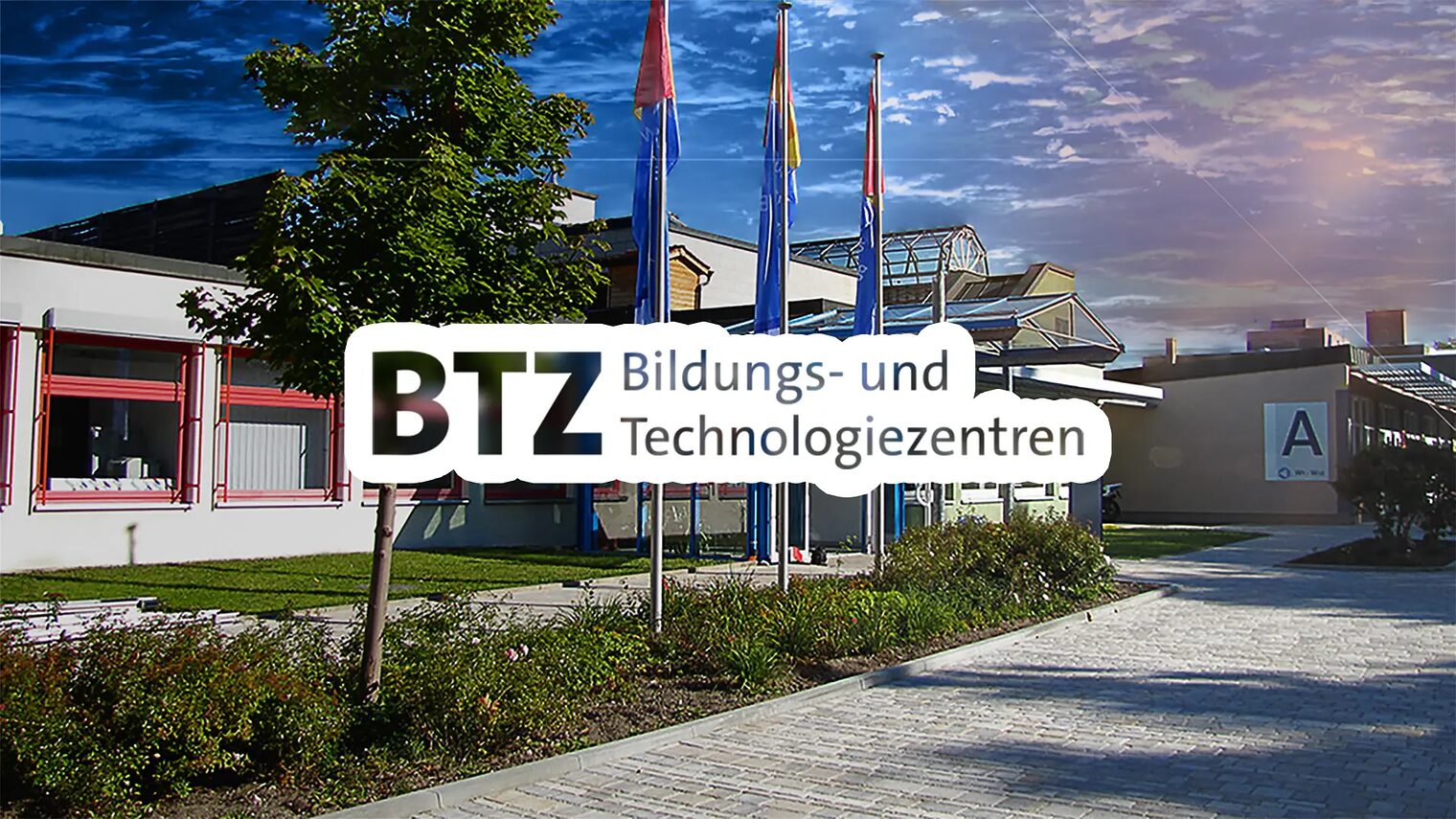 Ein Foto von unserem Bildungs- und Technologiezentrum 2. Zu sehen ist das Gebäude A. Über dem Foto liegt ein stilisierter Schriftzug: "BTZ - Bildungs- und Technologiezentren"